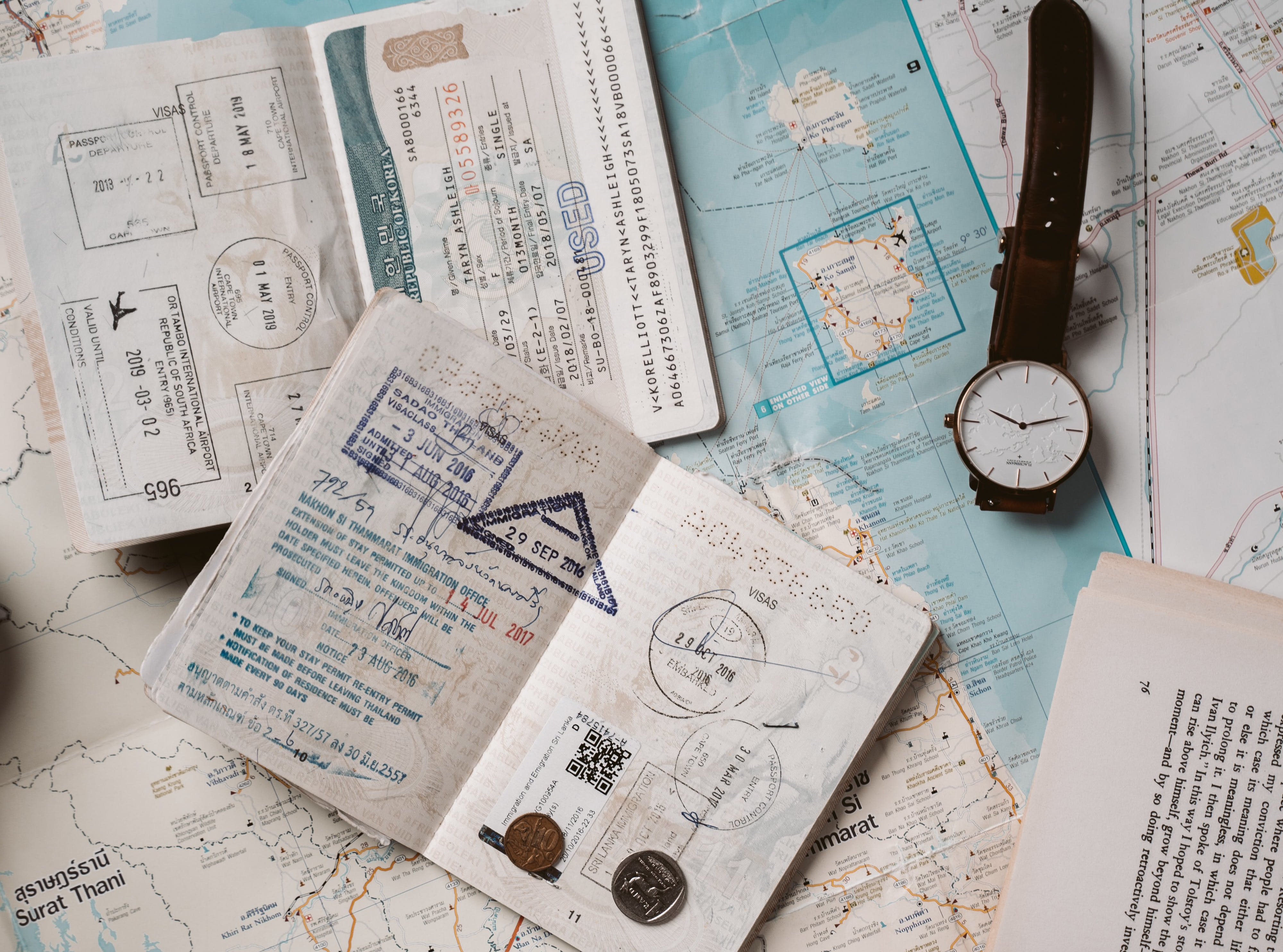 Reisepass mit vielen Stempeln und eine Uhr auf einer Weltkarte